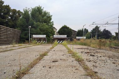 İtalya kırsalında bulutlu bir günde tren istasyonunun açıklığında üç çıkmaz yol.