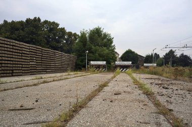 İtalya kırsalında bulutlu bir günde tren istasyonunun açıklığında üç çıkmaz yol.