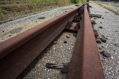 Çakıl taşlarının üzerindeki paslı demiryolu anahtarı yakından görülüyor