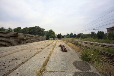 İtalya kırsalında bulutlu bir günde tren istasyonunun açıklığında üç çıkmaz yol.