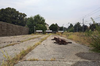İtalya kırsalında bulutlu bir günde tren istasyonunun açıklığında üç çıkmaz yol.