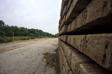 İtalya 'nın kırsal kesimlerinde bulutlu bir günde tren istasyonunun açıklığından görülen işlevsel bir demiryolunun yanında terk edilmiş raylar.