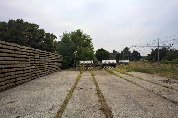 İtalya kırsalında bulutlu bir günde tren istasyonunun açıklığında üç çıkmaz yol.
