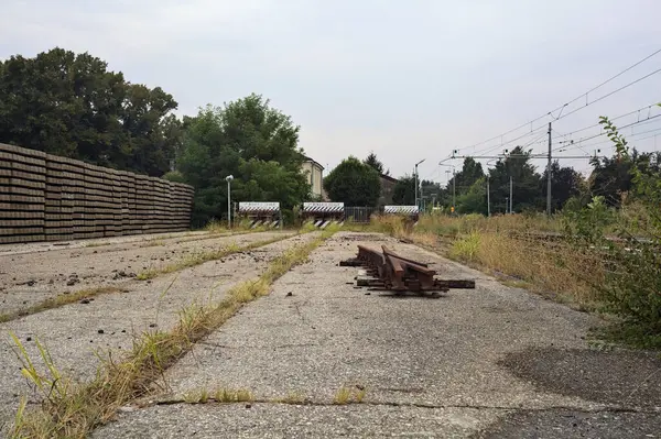 İtalya kırsalında bulutlu bir günde tren istasyonunun açıklığında üç çıkmaz yol.