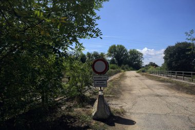 İtalya kırsalında güneşli bir günde beton bariyerlerle kapatılmış yıpranmış asfalt köprü