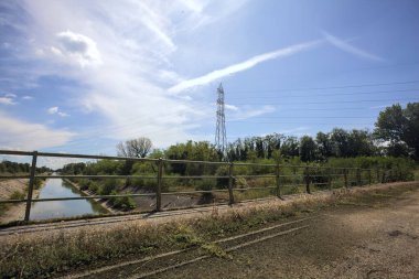 İtalya kırsalında güneşli bir günde ağaçlarla çevrili eğlence kanalı bir köprünün üstünden görülüyor.