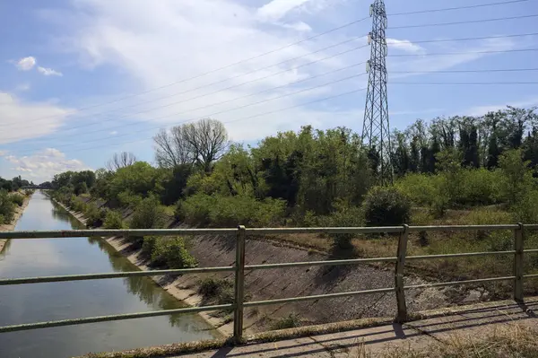 İtalya kırsalında güneşli bir günde ağaçlarla çevrili eğlence kanalı bir köprünün üstünden görülüyor.