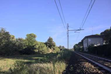 Gün batımında şehrin yanındaki ormandan geçen kablolu tren yolu.