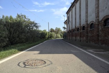 Kırsal alanda dar bir yol güneşli bir günde bir tarlanın ve bir ahırın yanında.