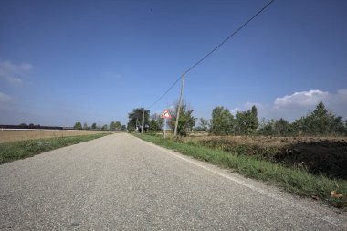 Güneşli bir günde kenarında bir tabela olan virajın yanındaki kır yolu.