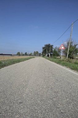 Güneşli bir günde kenarında bir tabela olan virajın yanındaki kır yolu.