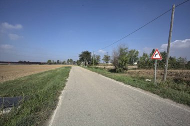 Güneşli bir günde kenarında bir tabela olan virajın yanındaki kır yolu.