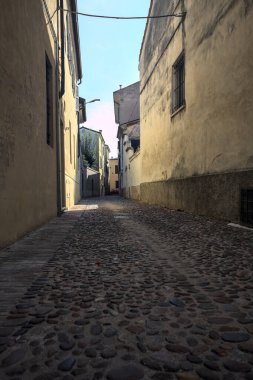 Bir İtalyan kasabasının gölgesinde kısmen kaldırımlı bir sokak.