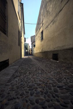 Bir İtalyan kasabasının gölgesinde kısmen kaldırımlı bir sokak.