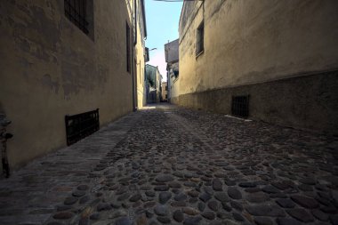 Bir İtalyan kasabasının gölgesinde kısmen kaldırımlı bir sokak.