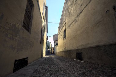 Bir İtalyan kasabasının gölgesinde kısmen kaldırımlı bir sokak.