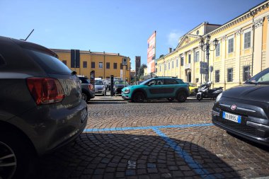 Park halindeki arabaların çerçevelediği İtalyan kasabasında bir sarayın önündeki meydan.