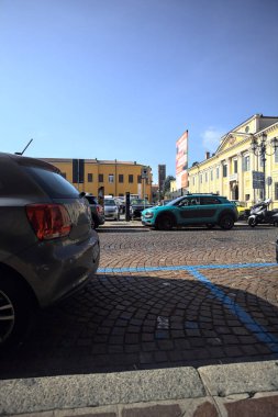 Park halindeki arabaların çerçevelediği İtalyan kasabasında bir sarayın önündeki meydan.