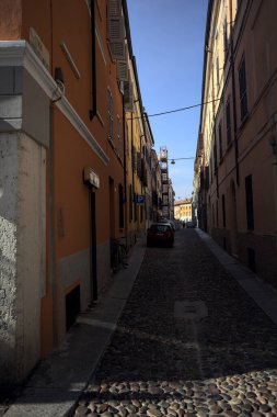 Bir İtalyan kasabasının gölgesinde kısmen kaldırımlı bir sokak.