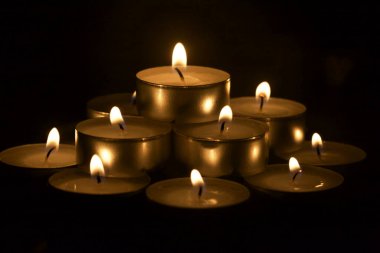 Karanlıkta sıralanmış mumlar yakından görülüyor.
