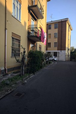 Gün batımında bir apartmanın yanında bitkilerle ve park edilmiş arabalarla çevrili bir sokak.