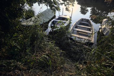 Gün batımında suda demirli kayıklar ve ağaç yansımaları