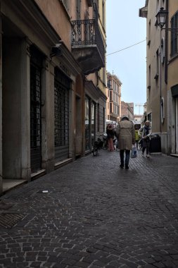 Dükkanları olan kaldırımlı bir sokak ve bir İtalyan kasabasından geçen insanlar.