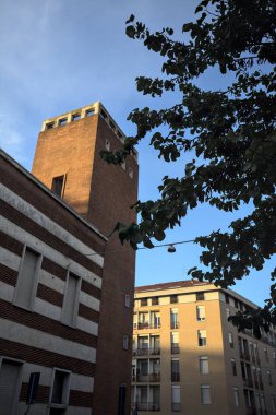 Günbatımında bir İtalyan kasabasında bir ağaç tarafından çerçevelenmiş modern bina.