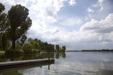 Nehir ve gökyüzünün su üzerindeki yansıması çerçevede kıyıdan bir parça