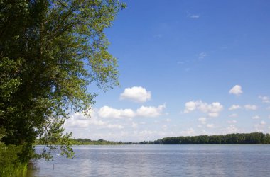 Nehir ve gökyüzünün su üzerindeki yansıması çerçevede kıyıdan bir parça
