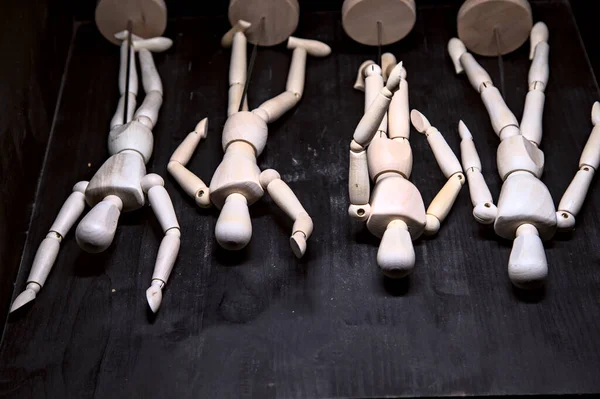 Wooden figurines laying on the ground posing like they are relaxing