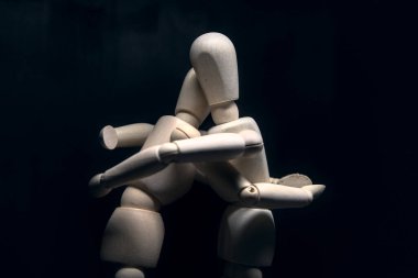 Siyah arka planda birbirine sarılan iki tahta heykel.