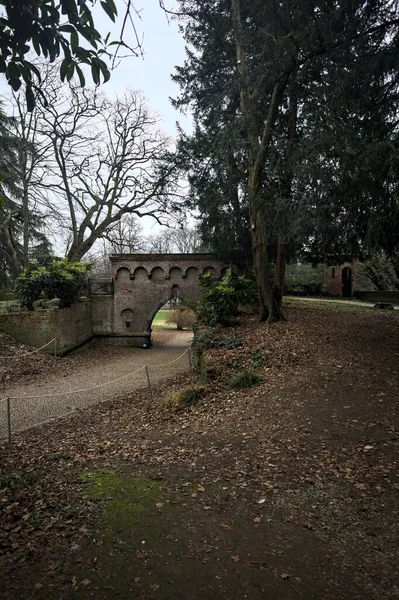 Gravel path that passes under a brick bridge in a park in autumn