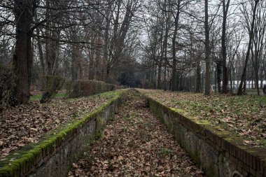 Sonbaharda bir parktaki duvarın yanındaki hendek yapraklarla dolu.