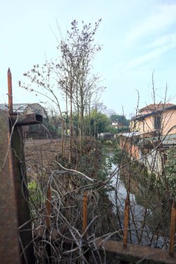 Terk edilmiş bir deponun önünde, köydeki bir su deresinin yanında.