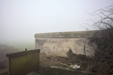 Sisli bir günde bir derenin yanındaki sınır duvarı.
