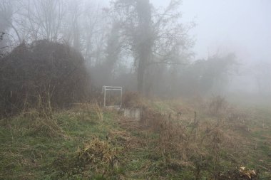 Weir sisli bir günde kirli bir patikanın kenarında