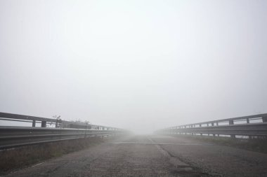 Sisli bir günde, nehri aşan asfalt köprü.