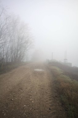Weir sisli bir günde kirli bir patikanın kenarında