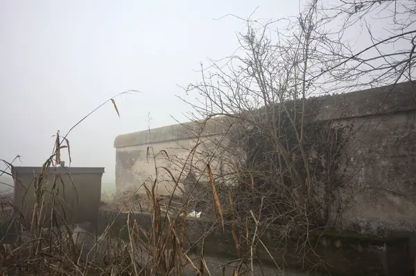 Boundary wall next to a creek on a foggy day