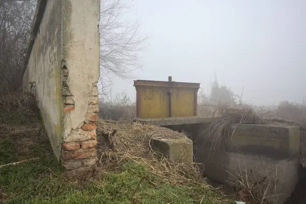 Boundary wall next to a creek on a foggy day
