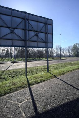 Bir reklam panosunun arkasındaki köy yolu.