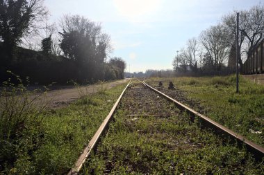 Terk edilmiş demiryolu rayları bir deponun yanında.