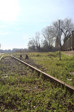 Terk edilmiş demiryolu rayları bir deponun yanında.