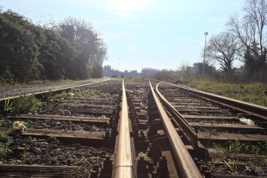 Terk edilmiş demiryolu rayları bir deponun yanında.