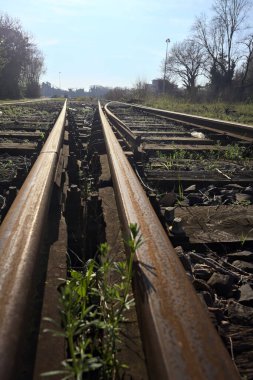 Terk edilmiş demiryolu rayları bir deponun yanında.