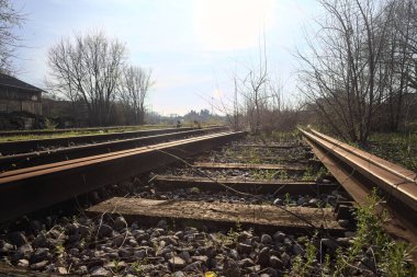 Terk edilmiş demiryolu rayları bir deponun yanında.