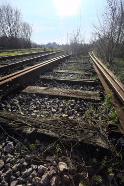 Terk edilmiş demiryolu rayları bir deponun yanında.