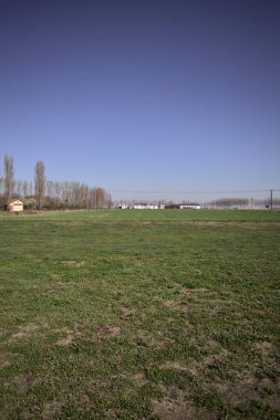 Yanı başında ağaçlar ve ufukta İtalya kırsalında bir köşk olan boş bir çayır.