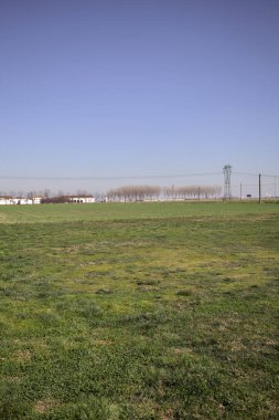 Yanı başında ağaçlar ve ufukta İtalya kırsalında bir köşk olan boş bir çayır.